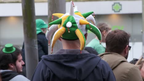 Harlequin-hat-in-green-and-yellow-in-crowd-of-people-watching-St