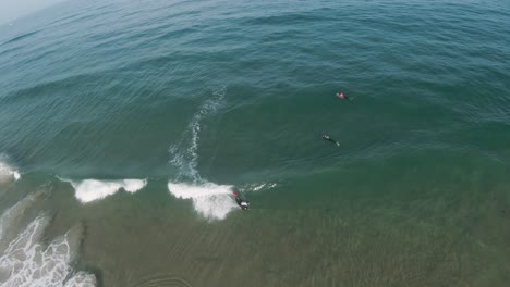 High-aerial-slow-motion-FPV-overview-of-skilled-bodyboarder-performing-an-ARS-air-roll-spin-maneuver-on-open-wave-face-on-sunny-clear-day-with-sand-pulling-from-beneath-water