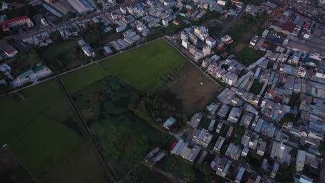 Suburb-of-Ho-Chi-Minh-City,-Vietnam-with-rice-field,-residential-area,-factories-and-urban-sprawl-as-seen-from-aerial-view-on-sunny-afternoon