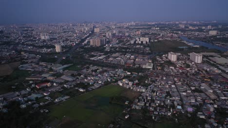 Suburb-of-Ho-Chi-Minh-City,-Vietnam-with-rice-field,-residential-area-and-urban-sprawl-as-seen-from-aerial-view-on-sunny-afternoon