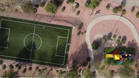 Top-down-shot-of-a-football-pitch-and-a-children's-play-park-and-trail