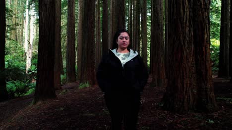 Girl-Exploring-In-Awe-of-California-Redwood-Forest,-Drone-Backwards-Follow