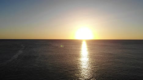 Luftaufnahme-Des-Goldgelben-Sonnenuntergangs-über-Dem-Meerwasser-In-Richtung-Horizont