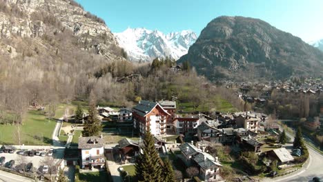 FPV-drone-aerial-in-alpine-resort-Courmayeur,-Aosta-Valley,-Italy-at-foot-of-Alps-Mont-Blanc-Monte-Bianco,-flying-over-mansion-and-forest