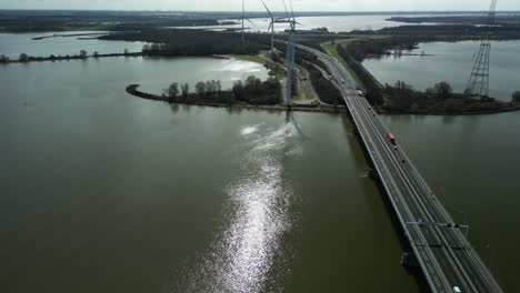 Drohne-Fliegt-Rückwärts-über-Einem-Fluss-Neben-Einer-Brücke-Mit-Einer-Nationalstraße