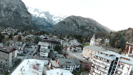 FPV-drone-aerial-over-alpine-mountain-resort-centre-and-church-of-Courmayeur,-Aosta-Valley,-Italy,-Mont-Blanc-Monte-Bianco,-flying-over-houses