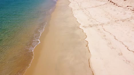 Aerial-view-of-sandy-beach-and-ocean-with-waves
