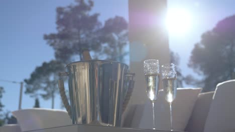 Champagner-Und-Gläser-Auf-Dem-Terrassentisch-Mit-Sonne-Im-Hintergrund
