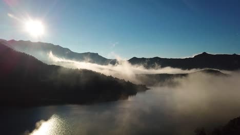 Drone-footage-over-a-lake-with-fog-over-the-water