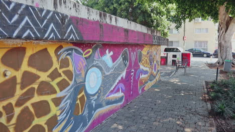 Eine-Lebendige-Energie-Der-Straßenkunstszene-Von-Tel-Aviv-Mit-Farbenfrohen-Graffiti-Eines-Grauen-Wolfes-Und-Einer-Gelben-Giraffenstruktur-Vor-Einem-Einfarbigen-Violetten-Hintergrund