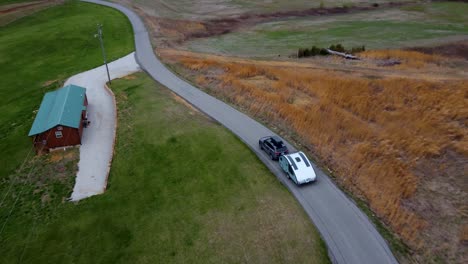 Sports-Utility-Vehicle-tows-teardrop-camper-down-winding-country-road_aerial-drone-in-the-spring