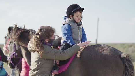 Kind-Umarmt-Das-Pferd-Liebevoll-Mit-Unterstützung-Des-Tiertrainers