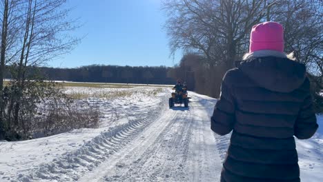 Girl-Walking-At-Snowy-Country-Road-Meet-A-Man-Driving-An-ATV-Pulling-A-Sled-With-Kids-At-Winter