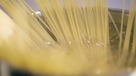 Close-up-slomo-pan-of-spaghetti-straws-in-pot-of-boiling-water