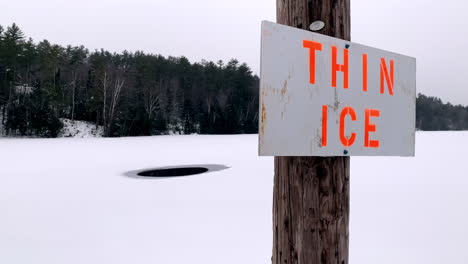 Closeup-of-a-Thin-Ice-Sign-in-front-of-a-Frozen-Lake