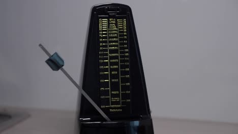 Sped-up-metronome-swinging-to-beat-of-music,-close-up-time-lapse