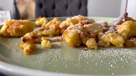 Slow-motion-close-up-of-sprinkling-traditional-Austrian-Pancake-named-Kaiserschmarrn-with-powdered-sugar