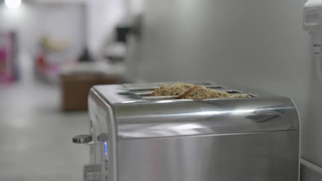 A-man-puts-two-slices-of-bread-into-a-toaster-in-a-kitchen-at-home