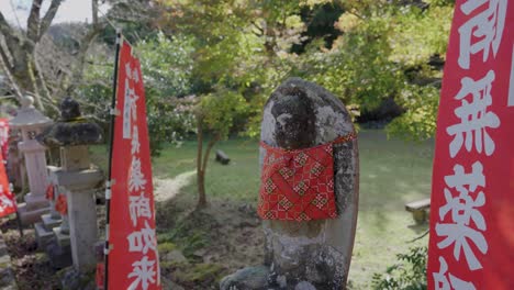 Jizo-Statue-with-red-scarf-at-Temple-in-Kinosaki-Onsen,-Peaceful-Fall-Japan
