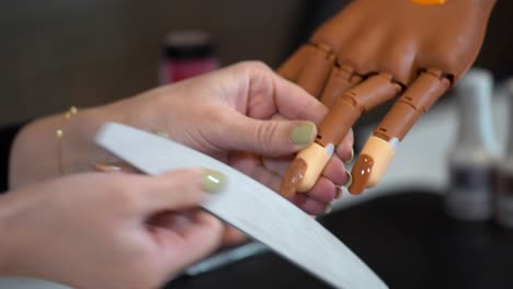 Manicure-creates-the-correct-shape-of-nails-on-a-prosthetic-hand-with-a-Nail-file