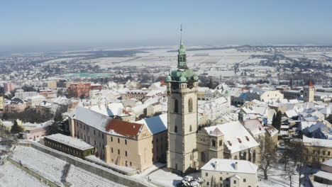 Small-riverside-town-with-a-church-clocktower-in-winter-snow,rotating