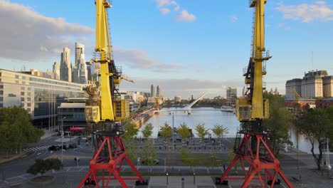Aerial-dolly-forward-flying-between-two-old-port-cranes-and-revealing-touristic-Puerto-Madero-neighborhood