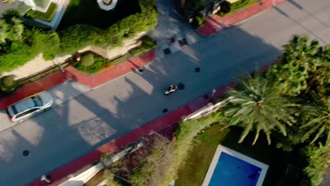 Person-driving-through-luxury-home-area-on-motorbike-in-aerial-view