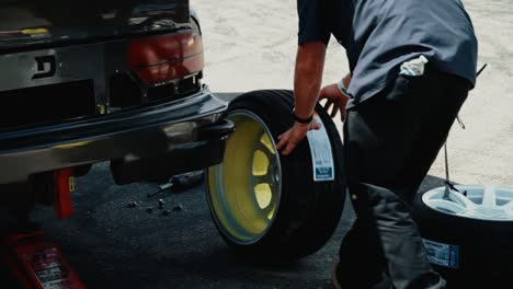 Man-Rolling-a-Wheel-and-Tire-to-Install-on-Car-before-a-Drifting-Race