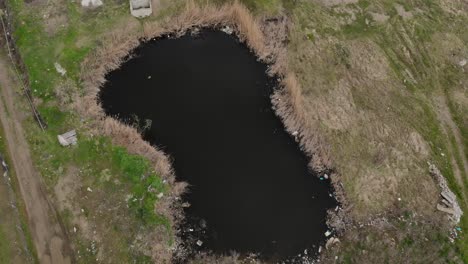 Aerial-view-of-a-property-with-a-small-polluted-lake-darkened-by-waste