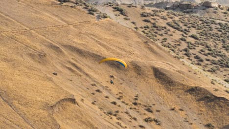 A-paraglider-floats-over-the-mountain-desert-landscape---slow-motion