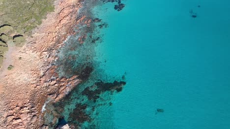 Aerial-drone-topdown-moving-towards-the-ocean-with-crystal-clear-calm-turquoise-water-in-castle-rock-Western-Australia
