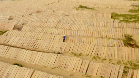 Drone-view-of-a-worker-is-drying-rice-paper-on-the-Rice-paper-village-in-Binh-Dinh-province,-central-Vietnam