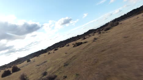 FPV-aerial-shot-flying-fast-over-a-large-open-countryside-field-in-England