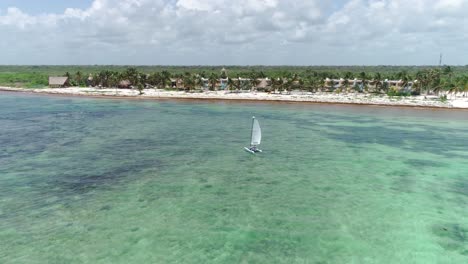 4K-Cinematic-drone-shot-making-an-arc-around-a-sailboat-cruising-on-the-turquoise-waters-of-the-Caribbean-in-Tulum,-Mexico