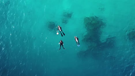 Aerial-shot-of-three-scuba-divers-floating-in-the-ocean,-Solomon-Islands