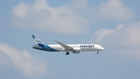 Westjet-liner-descending-and-preparing-to-land-in-airport,-blue-cloudy-sky