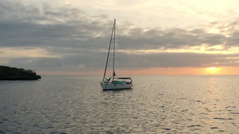 Sailboat-Floating-In-The-Ocean-With-A-Person-Lying-In-Hammock-At-Dusk