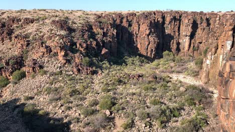 Upward-tilt-reveals-rusty-red-shattered-canyon-walls-in-arid-landscape