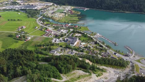 Panoramic-aerial-view-of-Loen-town-center-while-decending-from-mountain-Hoven--Summer-aerial-showing-center-with-road-fjord-buildings-and-river---Norway