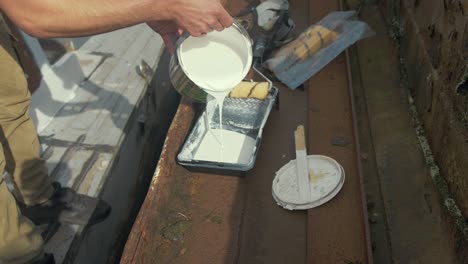 Pouring-white-paint-into-roller-tray.-WIDE-SHOT