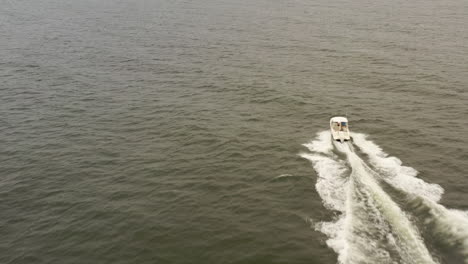 An-aerial-view-of-a-small,-white-fishing-boat-speeding-in-the-deep,-green-Atlantic-Ocean-near-Long-Island,-NY