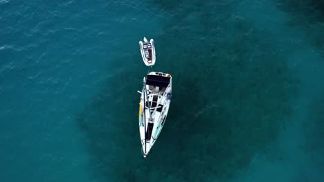 Top-Down-Aerial-View-of-Deserted-Anchored-Sailboat-and-Motorboat-in-Tropical-Sea