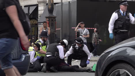 Metropolitan-police-officers-are-seen-between-two-stationary-cars-as-they-attend-to-a-medical-situation-after-a-man-collapsed-in-the-street