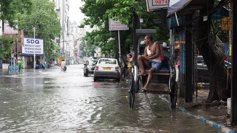 Ein-Rikschafahrer-Sitzt-In-Seinem-Karren,-Nachdem-Er-Nach-Starken-Regenfällen-In-Einer-überschwemmten-Straße-Steckengeblieben-Ist