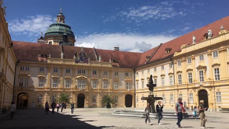 Pralatenhof-courtyard-in-Stiff-Melk-Castle-on-the-top-of-a-hill-above-the-Melk-town-with-tourists-walking-around
