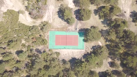An-old-tennis-court-in-red-and-green-with-many-trees-around