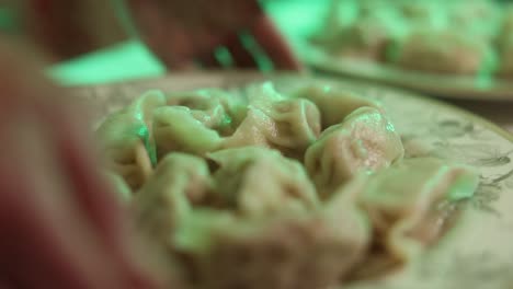 Close-up-shot-of-two-plates-of-freshly-boiled-dumplings,-chef-sets-the-plate-down