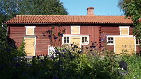 Idyllisches-Skandinavisches-Haus,-Rotes-Holzhaus-Mit-Blumen-Im-Garten