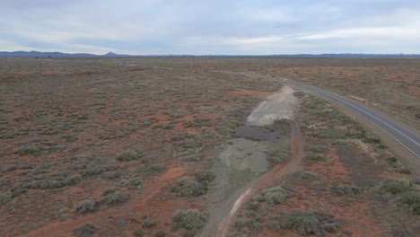 Aerial-fast-following-car-crossing-Australian-Outback-Countryside-road,-Arid-Landscape