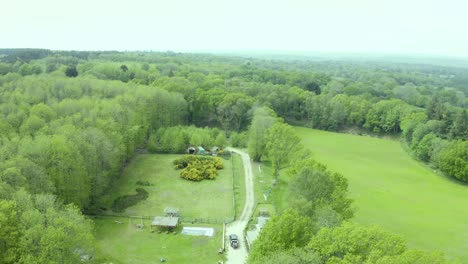 Countryside-farmland-aerial-view-above-green-woodland-trees-and-fields